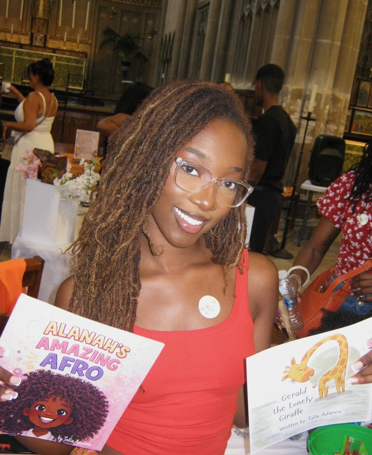 Talia Adanna holding her two picture books, Alanah's Amazing Afro and Gerald the Lonely Giraffe